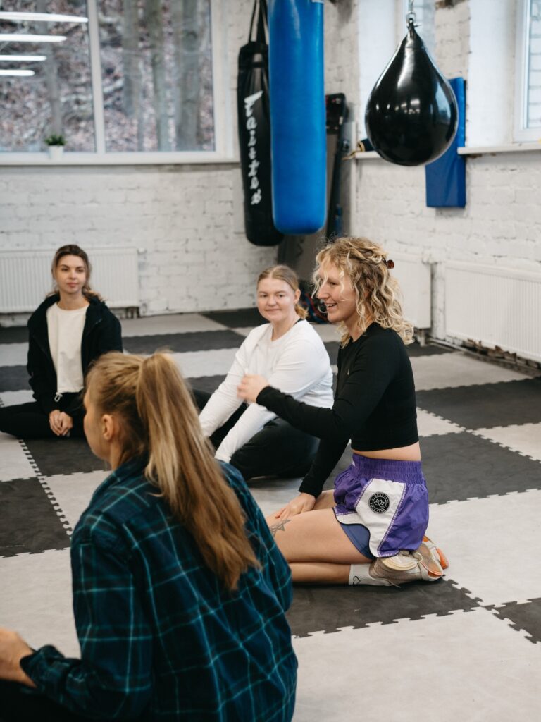 Moterys praktikuoja savigynos technikas poromis kovos menų salėje – Lygiosios savigynos dirbtuvės Kaunas